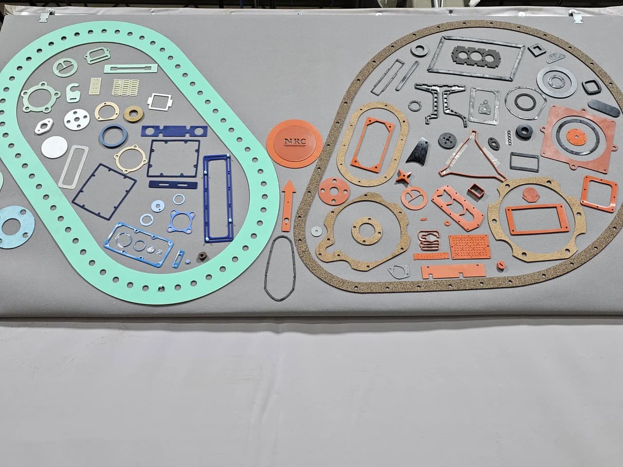 Dozens of complex die-cut gasket shapes laid out on a table