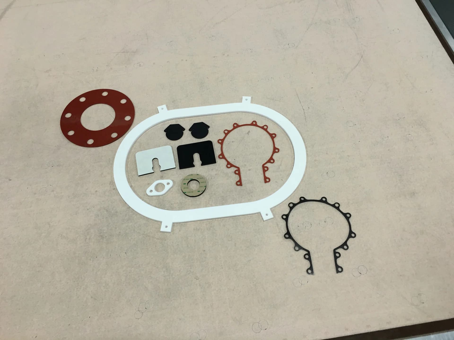 Die-cut flange gasket, frame gasket and small seals laid out on a table