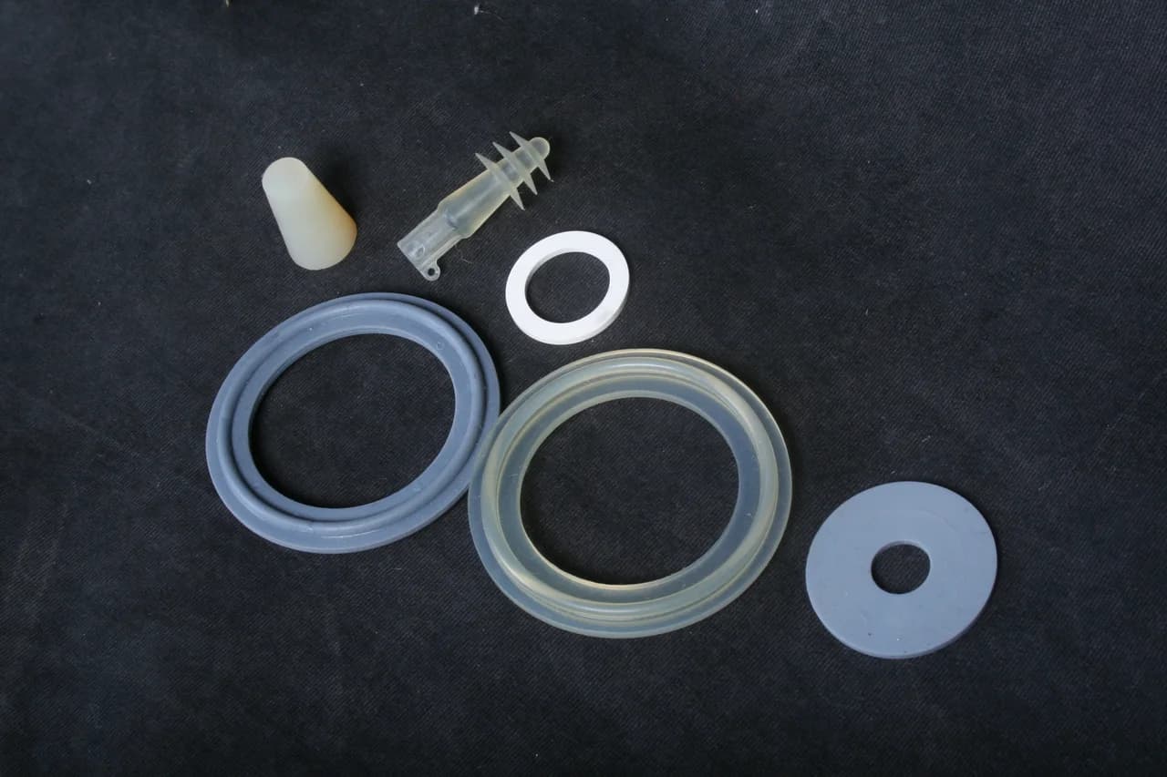 Clear molded gaskets and a white washer on a dark background